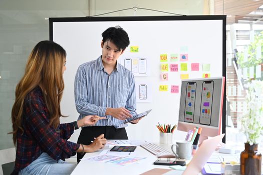 Two creative web designers are planning and discussing template layout to developing prototype wireframe for mobile phone.