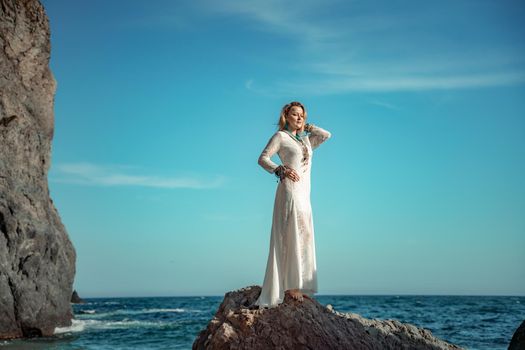 Middle aged woman looks good with blond hair, boho style in white long dress on the beach decorations on her neck and arms