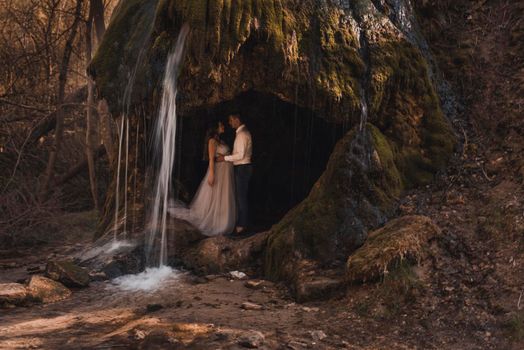 Family couple a man with a pregnant woman with a big belly in nature on the background of a waterfall.