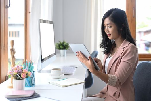 Concentrated businesswoman checking information on digital tablet.