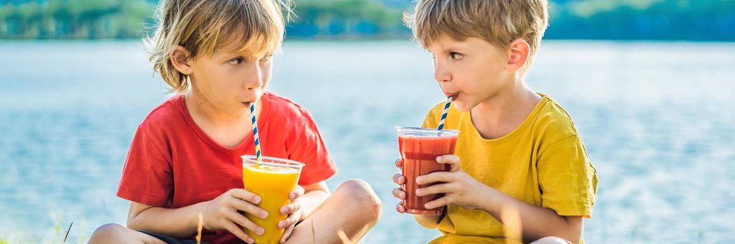 BANNER, LONG FORMAT Two boys drink healthy smoothies against the backdrop of palm trees. Mango and watermelon smoothies. Healthy nutrition and vitamins for children.