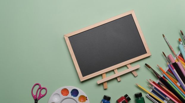 Empty chalkboard and stationery on green background. Back to school concept.
