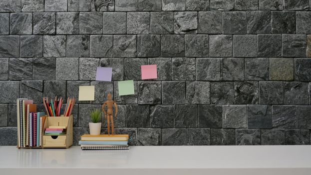 Home office desk with stationery and colorful sticky notes on brick wall background. Copy space for your advertise text.