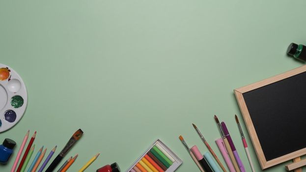 Chalkboard and school stationery on green background. Back to school concept.