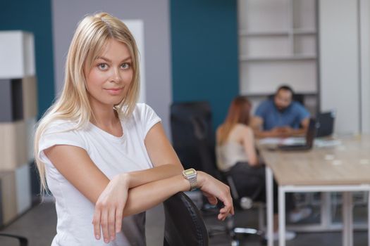 Confident young businesswoman smiling to the camera in modern open space office