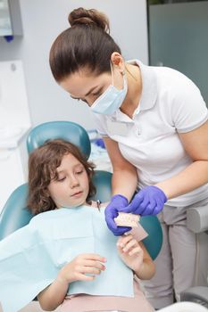 Vertical shot of a female dentist educating her young patient