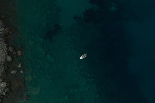 Aerial top nature view drone above yacht ship turquoise Adriatic sea in Albania. panoramic view marine. summer wallpaper. dark calm water rock bottom. mountain coast seaside. texture pattern mockup