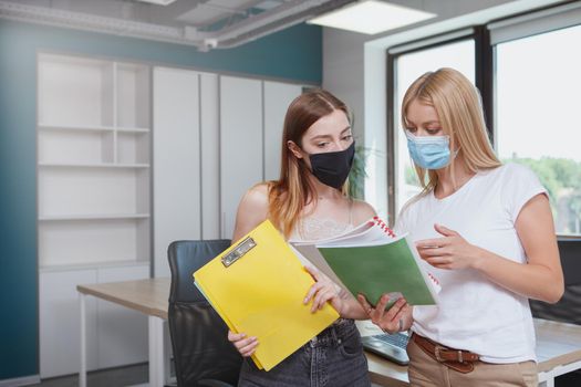 Female colleagues wearing protective face masks during coronavirus outbreak