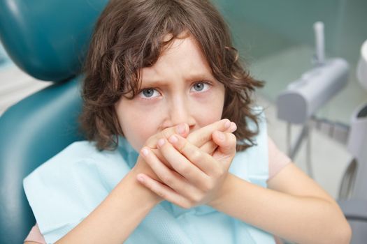 Close up of a scared boy refusing opening his mouth for dental treatment