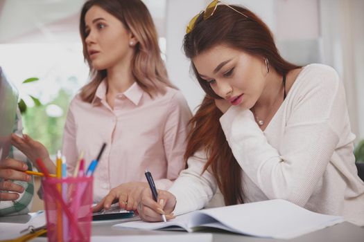 Cropped shot of a beautiful young woman doing her college assignment, writing in a textbook, copy space. Attractive female college student preparing for graduation exams