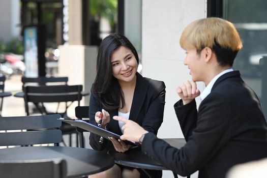 Two business colleagues having a discussion while sitting outdoor coffee shop.