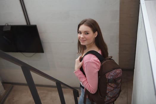 Happy young woman smiling to the camera walking down the stairs