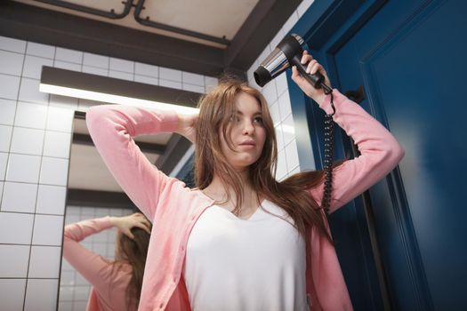 Low angle shot of a woman blow drying her hair