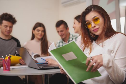 Confidence, success concept. Attractive young female college studentsmiling to the camera, while preparing for exams with her classmates, copy space