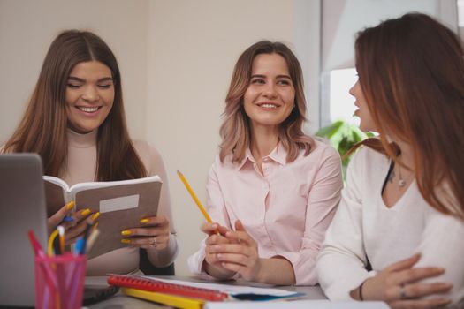 Females, equality, success concept. Beautiful cheerful young woman taling to her college friends, enjoying studying together. Lovely female students working on a project, preparing for exams