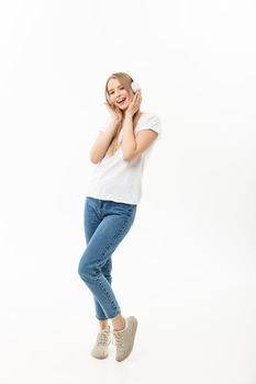 Lifestyle Concept: Portrait of a cheerful happy girl student listening to music with headphones while dancing isolated over white background.