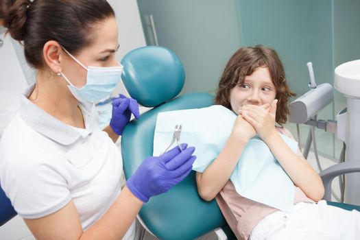 Scared boy refusing to open his mouth for dental examination at the clinic