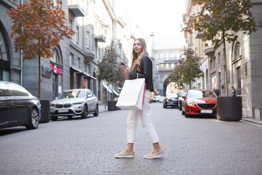 Woman crossing road in city center, carrying shopping bags