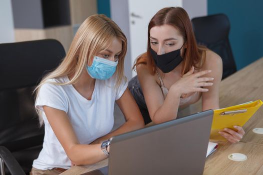 Female colleagues wearing protective face masks at the office