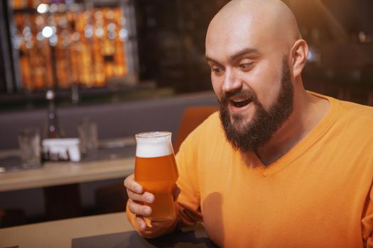 Excited man looking at his beer glass, copy space. Brewery, craft beer concept