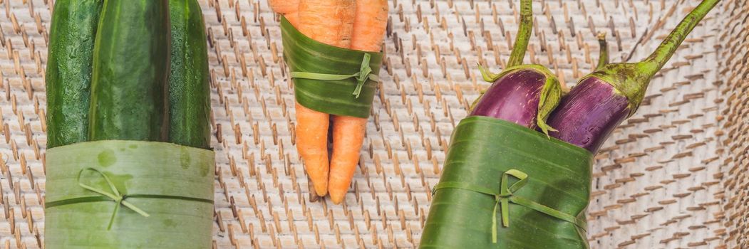 BANNER, LONG FORMAT Eco-friendly product packaging concept. Vegetables wrapped in a banana leaf, as an alternative to a plastic bag. Zero waste concept. Alternative packaging.