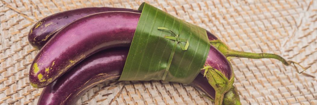 BANNER, LONG FORMAT Eco-friendly product packaging concept. Eggplant wrapped in a banana leaf, as an alternative to a plastic bag. Zero waste concept. Alternative packaging.