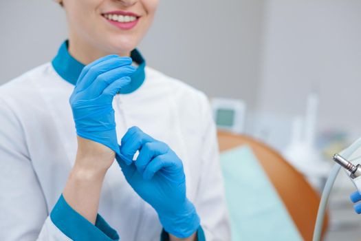 Cropped close up of a female doctor putting on rubber medical gloves, copy space. Professional dentist preparing for dental examination. Hygiene, uniform, protection concept