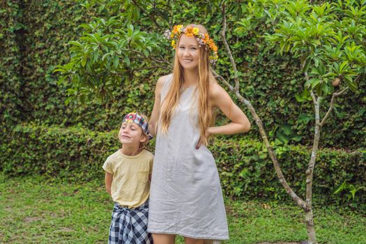 Boy tourist in sarong, national Balinese clothing and his mother with a wreath on his head.