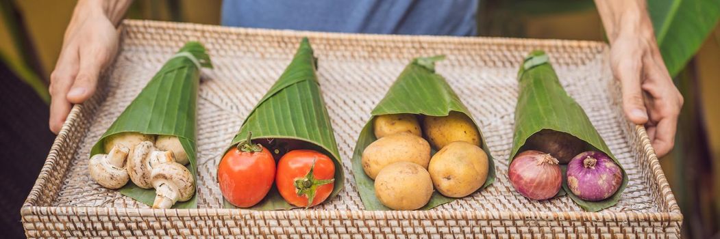 BANNER, LONG FORMAT Eco-friendly product packaging concept. Vegetables wrapped in a banana leaf, as an alternative to a plastic bag. Zero waste concept. Alternative packaging.