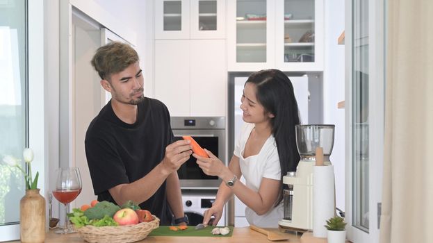 Loving young couple preparing ingredient for making vegetarian food in home kitchen.