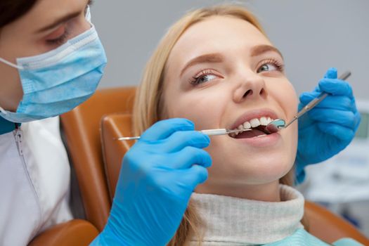 Close up shot of a beautiful young woman looking relaxed and happy while getting her teeth examined by professional dentist. Cropped shot of a female dentist working with her patient. Occupation, job