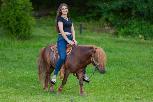 girl riding a pony on a green lawn