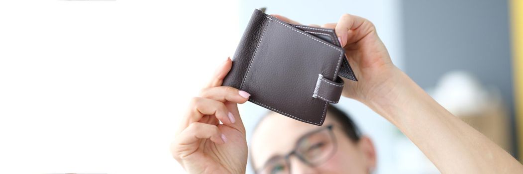 A woman looks into an empty purse, hands with a purse close-up. Unemployment, financial difficulties, inflation