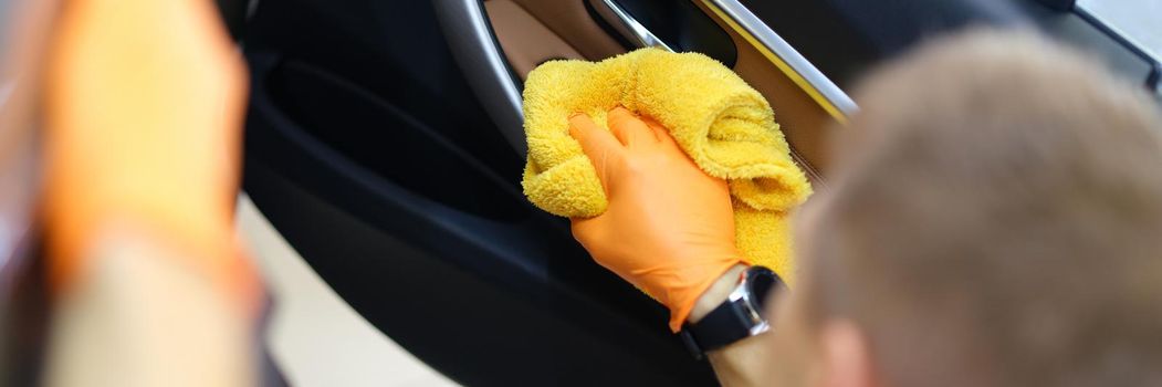 A man wipes a car interior with a towel, close-up. Car cleaning and wash, auto service, vehicle care. Detailing polishing