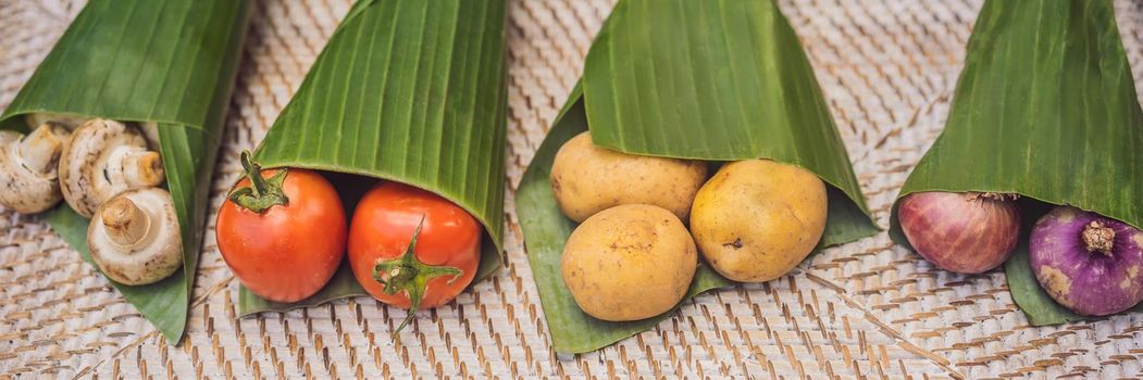 BANNER, LONG FORMAT Eco-friendly product packaging concept. Vegetables wrapped in a banana leaf, as an alternative to a plastic bag. Zero waste concept. Alternative packaging.