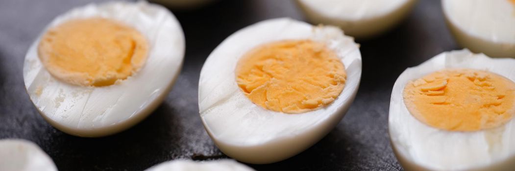 Boiled chicken eggs cut in half on a dark background, set close-up. Fresh organic food, salad preparation, breakfast