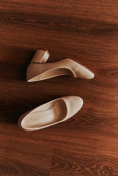 pair of women formal high heel shoes stands on a wooden textured brown floor parquet. morning gathering dressing bride accessories