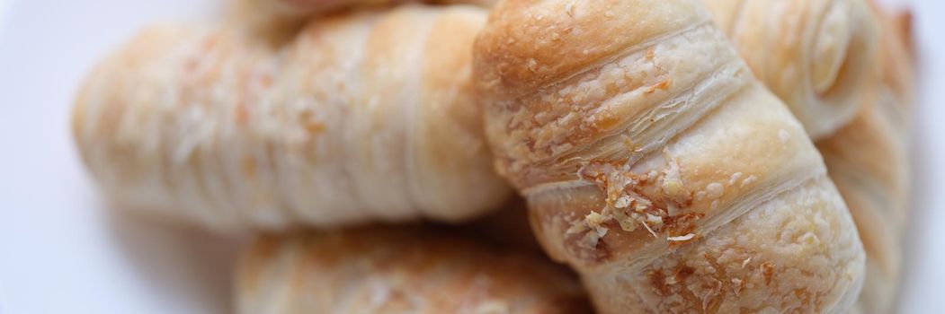 Hot tasty sausages in dough on a plate, puff bun, close-up. Homemade baked goods, cooking rustic breakfast