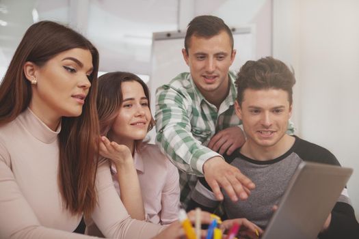 Online, internet concept. Group of young college students using laptop together, discussing assignment. CHeerful university friends browsing online, doing group study