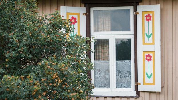 Window of an old house with painted red tulips on the shutters