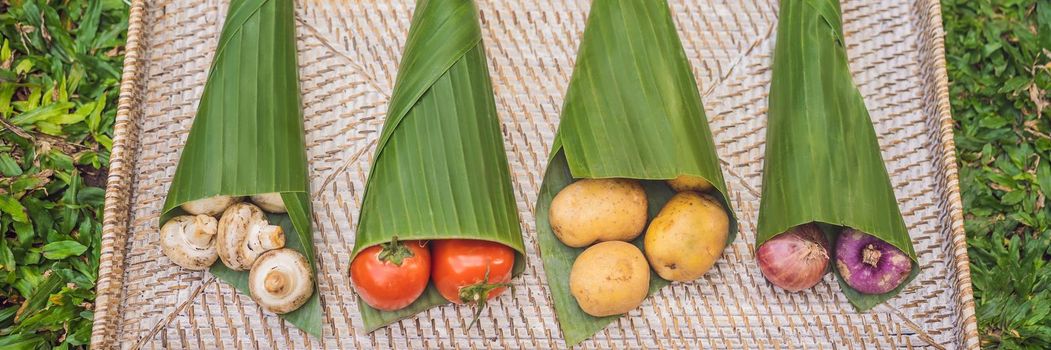 BANNER, LONG FORMAT Eco-friendly product packaging concept. Vegetables wrapped in a banana leaf, as an alternative to a plastic bag. Zero waste concept. Alternative packaging.