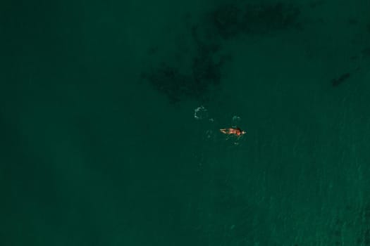 Aerial top nature view above green turquoise Thracian sea Greece Ellada. Beautiful young woman bikini swimming alone middle ocean water. girl in diving mask for snorkeling. wide panoramic view marine