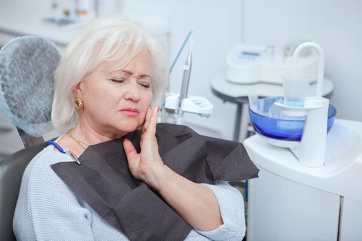 Senior woman having toothache, visiting dentist