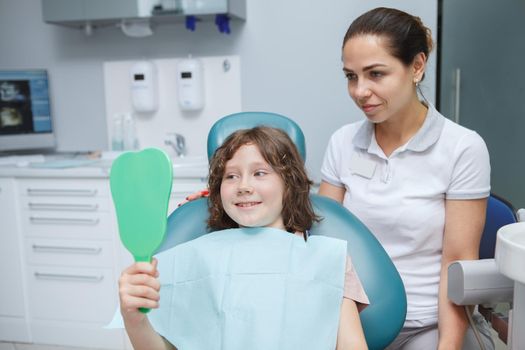Young female dentist working with child patient at her clinic