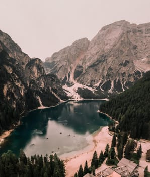 A large clear azure aquamarine green lake with brown wooden boats. High snow-capped stone mountains. Aerial top view from drone.