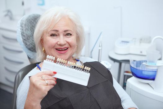 Lovely senior woman smiling to the camera, getting teeth whitening at dental clinic