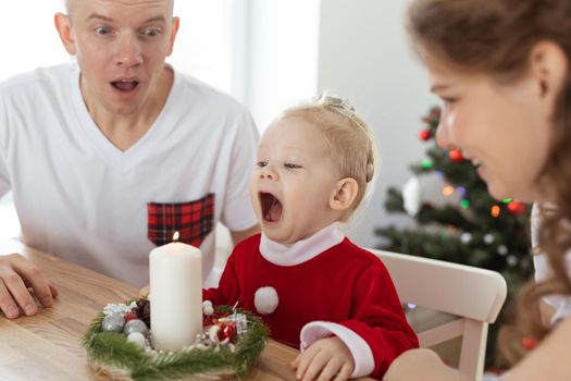 Baby child with hearing aid and cochlear implant having fun with parents in christmas room. Deaf and health