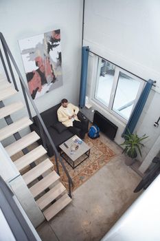 Vertical top view shot of a man resting on a couch at his hostel room