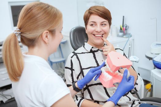 Cheerful young woman talking to her dentist during medical appointment