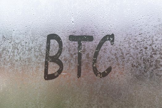 bitcoin handwritten on wet glass of night window.